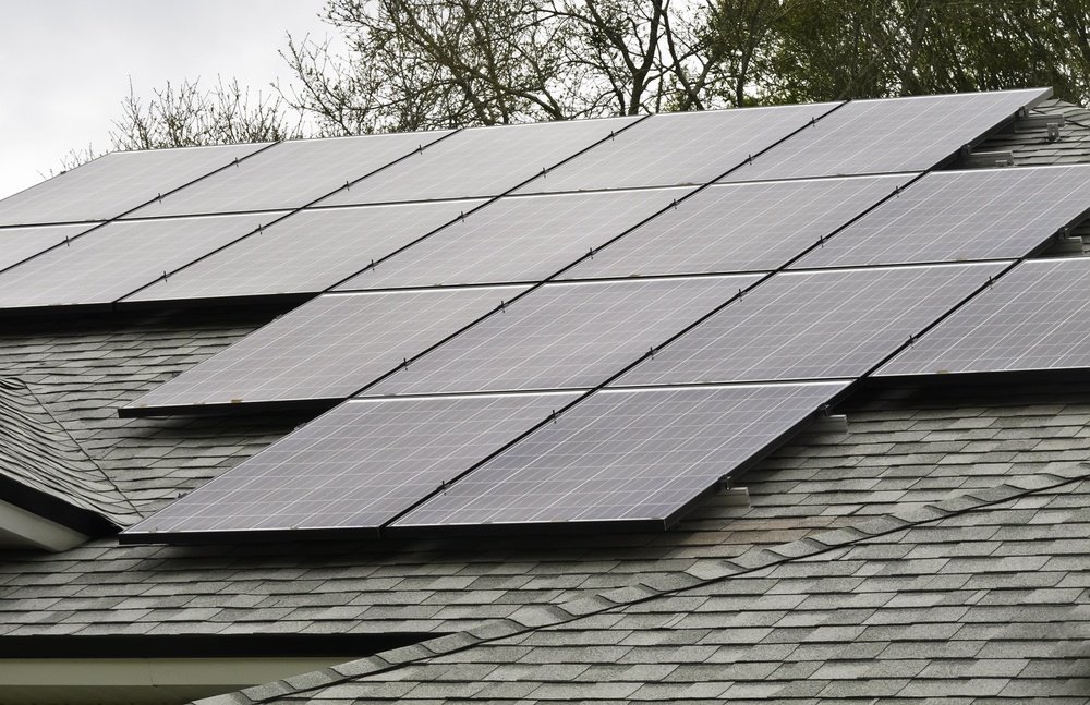 Array of solar panels on sloped roof of detached house on an overcast morning