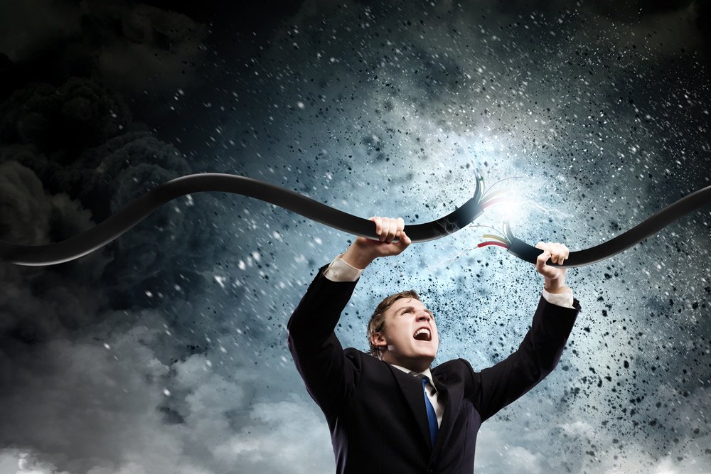 Young businessman tearing electricity cable with hands